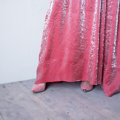 A woman in velvet pink with a black lace dress and black shoes in the interior. Close-up fragment. High quality photo