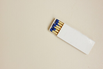 A white matchbox and blue matchsticks on a white background. The box is open. Cooking, hiking, cigarettes. Fire hazardous. Open fire. Copy space for text. top view. flat lay