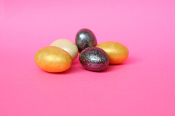 Chocolate eggs on a pink background for Easter. The eggs are multicolored. Happy Easter. Chocolate. Sweets for children and adults. Candy. Dessert. Copy space. Top view. Flat lay