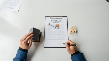 Real estate agent with wooden house example and top view calculator. Employees offer contracts to investors after successful approval and signing of construction contracts.