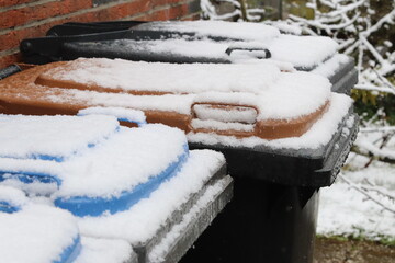 Rubbish cans with colorful hoods covered with snow. Waste separation. Recycling in Germany.