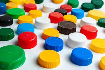 Colored plastic caps from bottles of water isolated on a white background. Close-up, top view. Recycling used plastic - a solution to the problem of plastic contamination.
