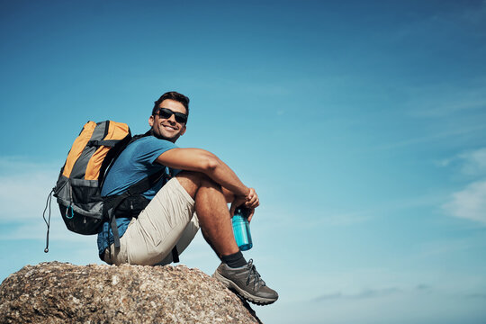 Look at this amazing view. Portrait of a carefree young man taking a quick break from hiking up a mountain during the day.