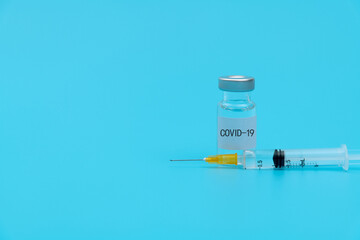 Syringe and covid-19 vaccine on blue background