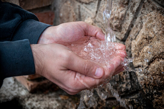 Mani che raccolgono acqua da una fonte per bere