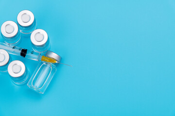 Group of vaccines and syringe on blue background