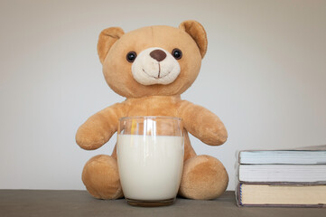 Brown teddy bears and a glass of fresh milk with books. Education and health concept.