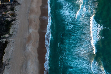 Aerial view top down of waves breaking on the beach in Kill Devil Hills North Carolina at sunset