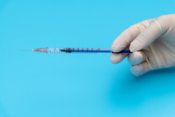 Hand holding syringe on blue background