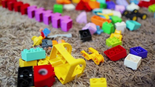 multi-colored blocks of plastic children's constructor are scattered on the carpet