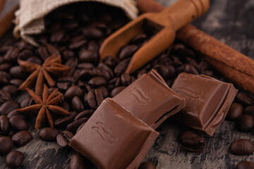 chocolate, cinnamon sticks  and coffee beans on wooden background