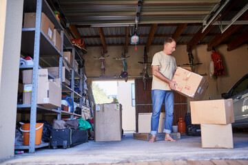 Clearing out some things. Shot of a man carrying a box in a garage.