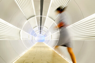 Woman walking in long futuristic tunnel
