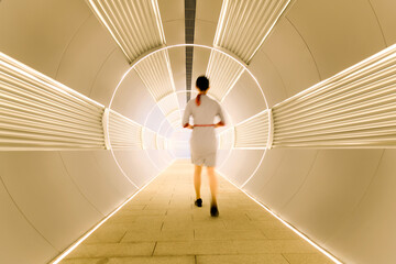 Woman walking in long futuristic tunnel