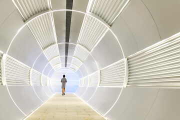 Woman walking in long futuristic tunnel