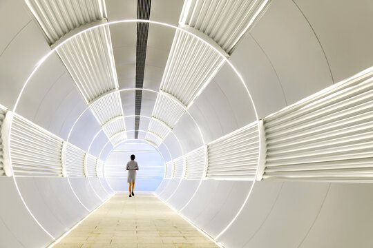 Fototapeta Woman walking in long futuristic tunnel