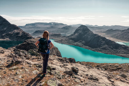 Girl with a backpack on a trip in the mountains. Famous Besseggen trekking in Norway. Epic lake view.