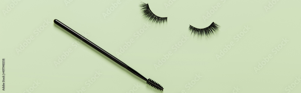 Wall mural Creative layout with eyelashes and brush mascara. Closed eyes on green background