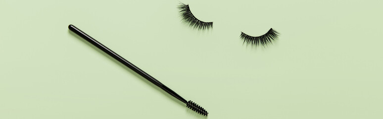Creative layout with eyelashes and brush mascara. Closed eyes on green background