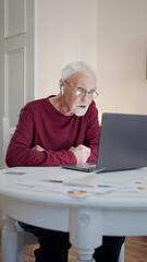 Fototapeta premium Grandfather in glasses and with wireless headphones communicates via video link