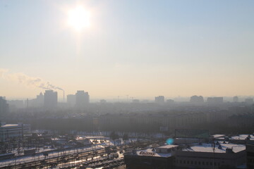 A residential area with typical Soviet arhitecture in the foreground on a sunny foggy day