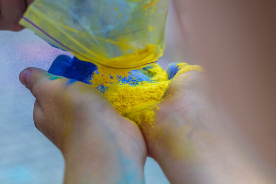 girls hands holding paints holi flag of ukraine. Ukraine will win. Pray for Ukraine. Holi festival. Blue and yellow colors. 