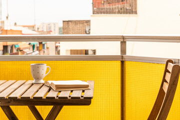 Terrace with wooden table and chairs to comfortably read a book and yellow glass and aluminum enclosure