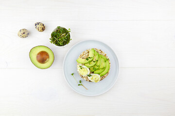 Wholegrain toast with egg, avocado and micro-greenery on a white wooden background. Healthy breakfast, vegetable food. Flat lay, top view. 