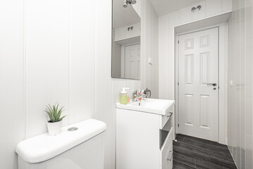 Fototapeta na wymiar Bathroom with white resin sink, white wood furniture and white wood carpentry