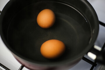 Two boiled brown eggs in a pot of boiling water