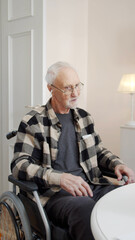 A woman shows an elderly man in a wheelchair how to use headphones. She plays his favorite songs