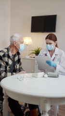 An elderly man in a wheelchair talks about his health problems. Nurse keeps records