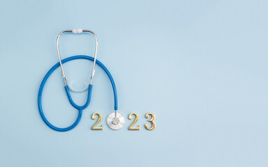 Stethoscope and metal numbers 2023 on blue pastel background with copy space for your design. Happy...