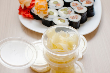 White spicy ginger in a plastic container. Use with rolls and sushi. Traditional Japanese food.