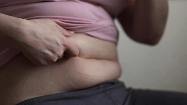 obesity, big waist, female hands holding a fat belly, unhealthy diet, overweight problem