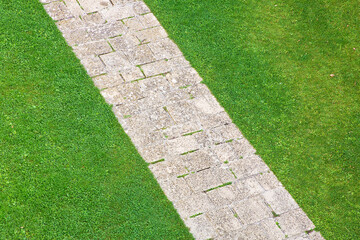 Pedestrian old stone footpath on a grass area of a public park