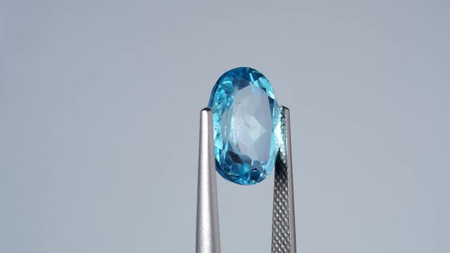 natural blue topaz oval cut in the turning tweezers