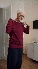 Fototapeta premium An elderly man turns on a workout video on his laptop. He does arm exercises with his carefree daughter