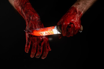 Man holding knife with bloody hand on black background.  © Михаил Решетников