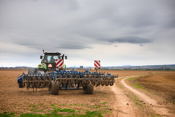 Spring soil preparation for planting using a tractor with a cultivator