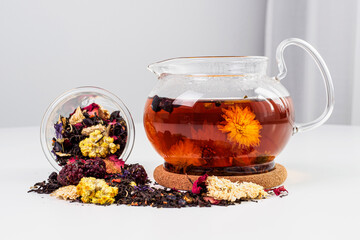Floral black tea brewed in a transparent teapot. A hot drink on the table with a scattering of tea...