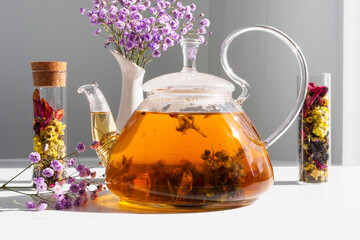 Floral black tea brewed in a transparent teapot. Hot drink on the table and granulated tea in a...