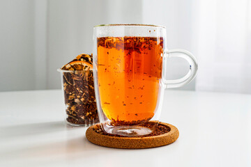 Rooibos tea in a transparent thermos mug on the table close-up. Visual for tea sample. Method of...