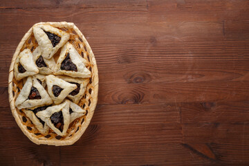 Gomentashash with poppy seeds and prunes freshly baked for the Purim holiday on a wooden table.copy space.
