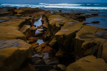  2022-04-09 THE ROCKY SHORELIN EIN LA JOLLA CALIFORNIA WITH WATER MOVING THROGUH THE ROCKS WTH A NICE REFLECTION AND WAVES COMING ON SHORE