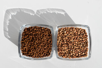 Close up of buckwheat tea granules and buckwheat groats in glass bowls on white background, natural herbal drink.