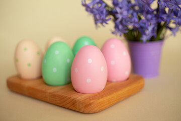 Fototapeta na wymiar Pastel Easter eggs in the wooden tray.Violet flowers on background.