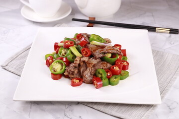 Spicy mandarin duck pepper fried beef in a dish side view on grey background singapore food