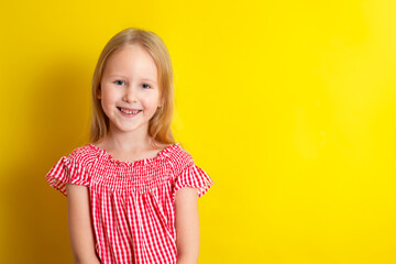 Portrait of a cute beautiful smiling blonde girl on a yellow background. Space for text.