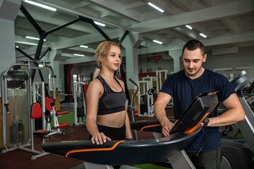 Female athlete with assistant personal trainer running on treadmills